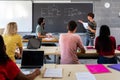 Teen male high school student giving oral class presentation in front of multiracial classmates. Teacher taking notes. Royalty Free Stock Photo