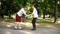 Teen male teaching girl to skateboard, riding awkwardly, youth and hobbies Royalty Free Stock Photo