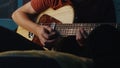 Teen musician playing guitar at night