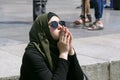Teen Muslim girl in hijab and sunglasses sitting on the pavement on street dreaming of. Kyiv, Ukraine