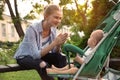 Teen nanny with baby in stroller playing in park