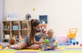 Teen nanny and cute little baby playing with toys