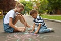 Teen nanny and cute little boy drawing sun with chalks