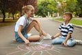 Teen nanny and cute little boy drawing sun with chalks Royalty Free Stock Photo