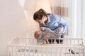 Teen nanny putting cute little baby in crib. Daytime sleep