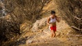 Teen in red shorts running on trail on mountain