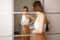 Teen self-esteem problem, triple teen girl looking for fat on her body, standing at home in front of the mirror Royalty Free Stock Photo