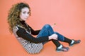 Teen sits down against an orange background