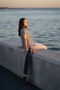 Teen skater girl at seaside sunset. Young woman enjoy summer evening at river or sea look at water Royalty Free Stock Photo