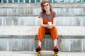 Teen skater girl sits on steps with blank coffee container in her hands.