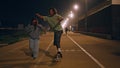 Teen skaters riding skate boards enjoying night street. Man balancing skateboard