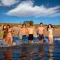 Teen surfers group running beach splashing Royalty Free Stock Photo