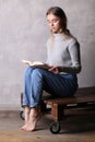 Teen in sweater reading a book. Gray background