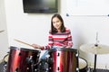 Smiling Girl Practicing Drums In Music School