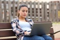 Teen using laptop in a bench in a park Royalty Free Stock Photo