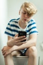 Teen using smartphone on toilet Royalty Free Stock Photo