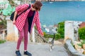 Teen volunteer girl with little cat in small coastal town. Young tourist calling cute abandoned hungry kitten. Authentic lifestyle