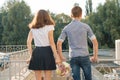 Teen youth couple boy and girl standing back, summer sunny day, girl holding bouquet of flowers in hand Royalty Free Stock Photo