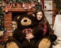 Teenag girl is embraces a big big teddy bear on christmas near fireplace Royalty Free Stock Photo