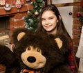 Teenag girl is embraces a big big teddy bear on christmas near fireplace Royalty Free Stock Photo