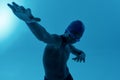 Teenage african boy sportsman in swimming cap and goggles having swim training while standing  over blue Royalty Free Stock Photo