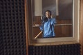 Teenage African singer wearing headphones, sings into microphone, working in a voice studio with enjoyment and happiness Royalty Free Stock Photo