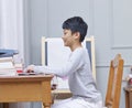 Teenage Asian boy surfing the net at home smiling Royalty Free Stock Photo