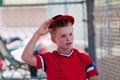 Youth baseball player taking hat off in dugout.