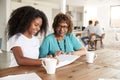 Teenage African American  girl looking through a photo album with her grandmother at home, close up Royalty Free Stock Photo