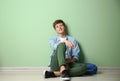 Teenage boy with backpack sitting on floor near color wall Royalty Free Stock Photo