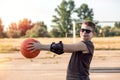Teenage boy basketball player, looking at the camera, pulled an orange basketball ball in his hands to the left towards the hoop, Royalty Free Stock Photo
