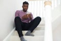 Teenage Boy Being Bullied By Text Message Sitting On Stairs At Home