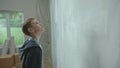 A teenage boy in a blue hoodie is inspecting a freshly painted wall. A young guy posing in a room against the background Royalty Free Stock Photo