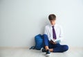 Teenage boy with book sitting on floor near light wall Royalty Free Stock Photo