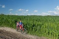 Teenage boy carrying his little sibling sister on baby bike seat on farm corn field summer dirt road Royalty Free Stock Photo