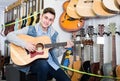 Teenage boy is choosing quality acoustic guitar Royalty Free Stock Photo