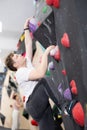 Teenage boy climbs steep artificial wall in sports complex and trains endurance Royalty Free Stock Photo