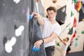 Teenage boy climbs steep artificial wall in sports complex and trains endurance Royalty Free Stock Photo