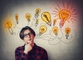 Teenage boy confident thinking, glowing light bulbs over head. Student guy dreamer wearing glasses, has different thoughts. Genius Royalty Free Stock Photo