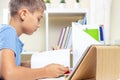 Teenage boy with digital tablet computer has lessons over video call, doing homework at table. Online learning at home Royalty Free Stock Photo