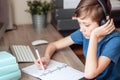 A teenage boy does homework, learns using a computer. Distance learning online. A child in quarantine in isolation Royalty Free Stock Photo