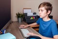 A teenage boy does homework, learns using a computer. Distance learning online. A child in quarantine in isolation Royalty Free Stock Photo