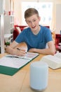 Teenage Boy Doing Homework Asking Digital Assistant Question Royalty Free Stock Photo