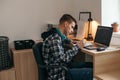 Teenage boy doing homework using computer sitting by desk in room alone Royalty Free Stock Photo