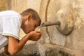 teenage boy drinks water from a spring,there is a place for an inscription Royalty Free Stock Photo