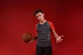 Fight On. A teenage boy is engaged in sport, he is looking at camera while holding basketball. Isolated on red Royalty Free Stock Photo