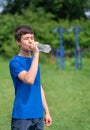 Teenage boy exercising outdoors, sports ground in the yard, he opens a bottle of water and drinks, healthy lifestyle Royalty Free Stock Photo