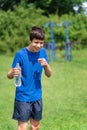 Teenage boy exercising outdoors, sports ground in the yard, he opens a bottle of water and drinks, healthy lifestyle Royalty Free Stock Photo