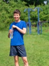 Teenage boy exercising outdoors, sports ground in the yard, he opens a bottle of water and drinks, healthy lifestyle Royalty Free Stock Photo