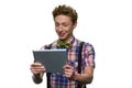 Teenage boy with facial expression of bewilderment or discontent is looking at tablet pc.